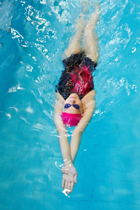young woman swims on back in the pool