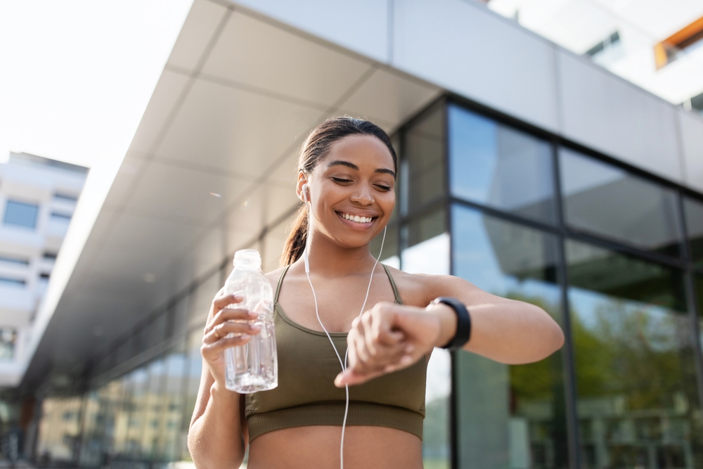 Young black woman looking at smartwatch, tracking fitness activity,